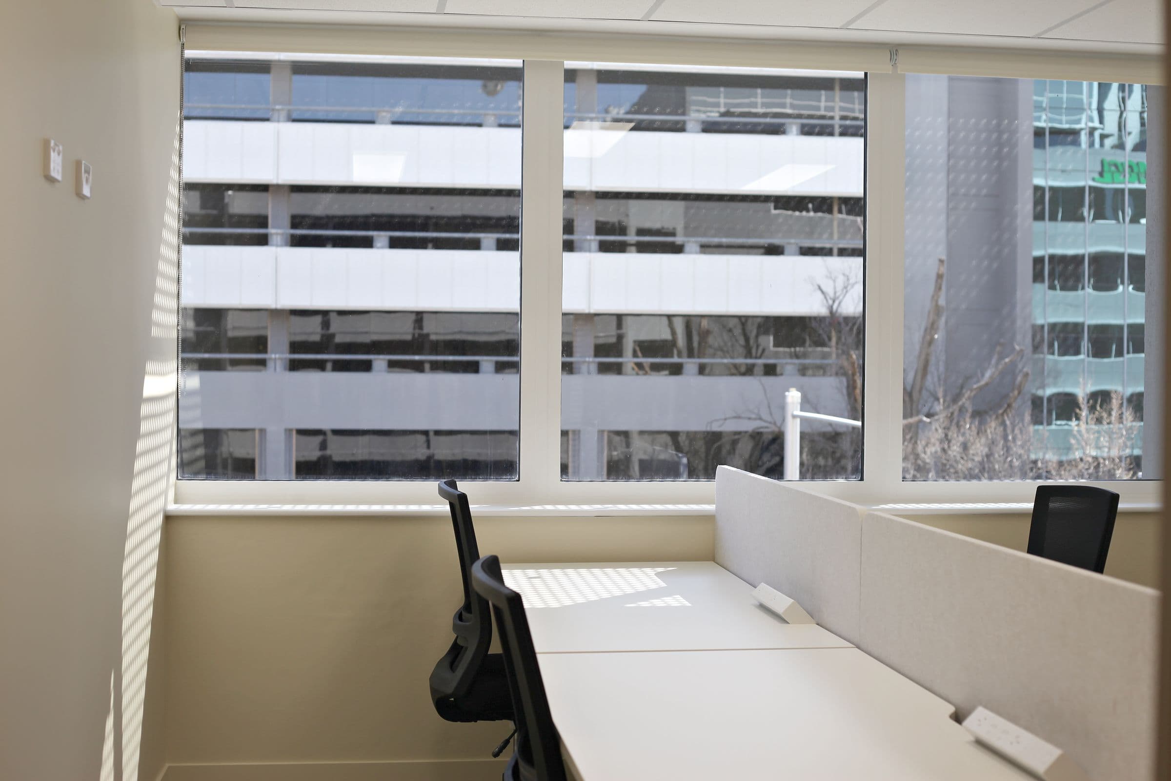 A private office with desks by a wide window at Workspace by black vc
